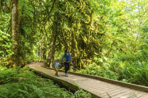 Mother and son enjoying a leisurely stroll on a wooden boardwalk amid the lush greenery of a
