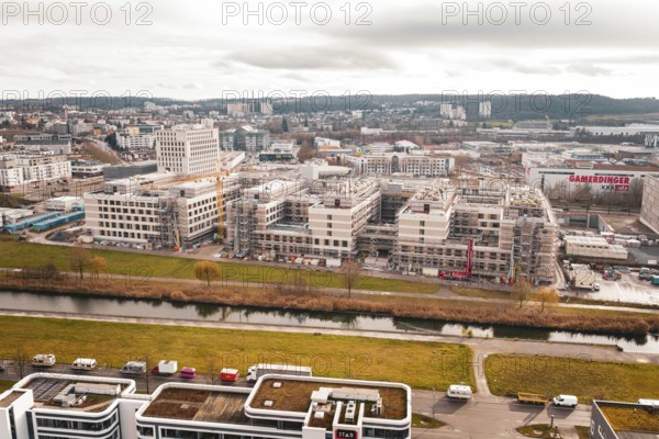 New hospital aerial view of an area with modern buildings, a river and a large construction site,