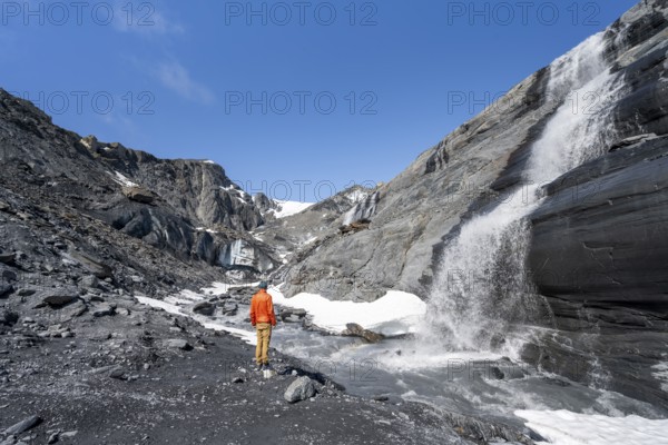 Tourist standing at a glacier stream, glacier ice and waterfall, Worthington Glacier State