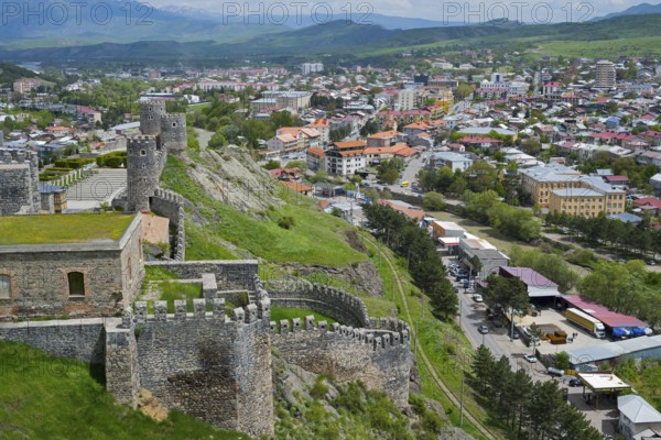 Panorama of a city with historic castle ruins on a hill under cloudy sky, Rabati Fortress,