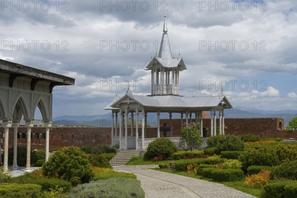 Elegant white pavilion in a well-kept garden with a curved path and mountain views, Rabati