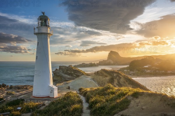The Castlepoint lighthouse on a rock, ocean, Deliverance Cove and Castle Rock in the background.