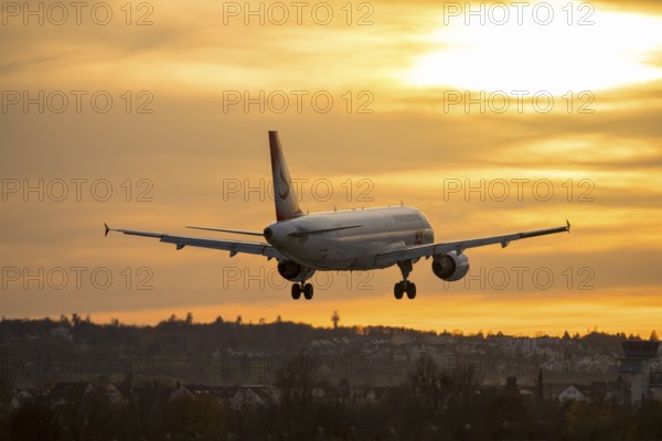 Airplane landing at sunset, orange light on horizon, Stuttgart airport, Leinfelden-Echterdingen,