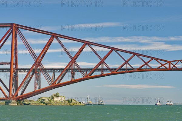 A section of a red bridge over a lake with passing boats, railway bridge, Firth of Forth,