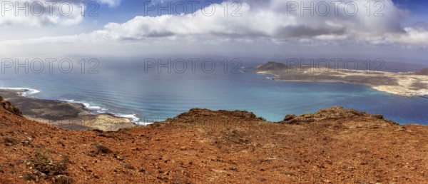 Wide coastline with blue ocean and sky, dotted with clouds overlooking La Graciosa, Haria