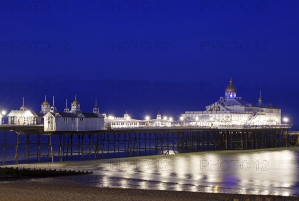 An illuminated pier stretches across the calm sea at night, Bournemouth, England, Great Britain
