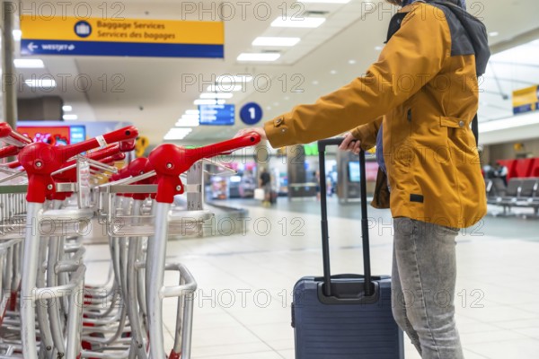 Tourist navigating the airport terminal with a luggage trolley, positioned near the baggage claim