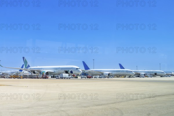 Several airplanes are parked on the tarmac at an airport, waiting for their next flights under a