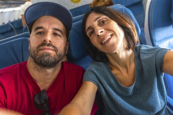 Happy couple taking a selfie on an airplane, enjoying their flight while capturing joyful moments