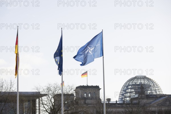 Flags of the Federal Republic of Germany, the EU and NATO in front of the Reichstag building,