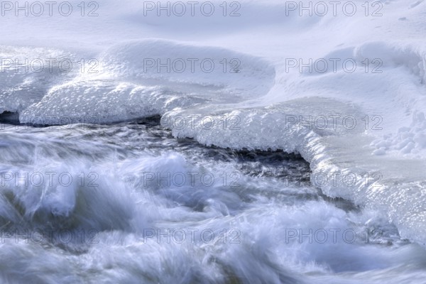 Ice formation formed by frost and freezing cold temperatures over running water of stream along