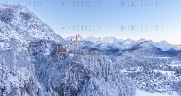 Neuschwanstein Castle is perched in the snowy alpine landscape, surrounded by peaceful forests