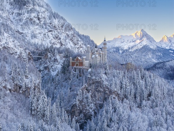Neuschwanstein Castle against a wintry alpine backdrop in early morning light, Schwangau near