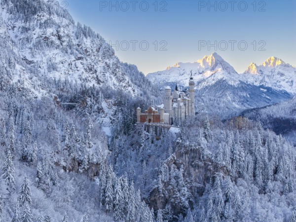 The magnificent Neuschwanstein Castle, surrounded by mountains and glowing snow in the morning