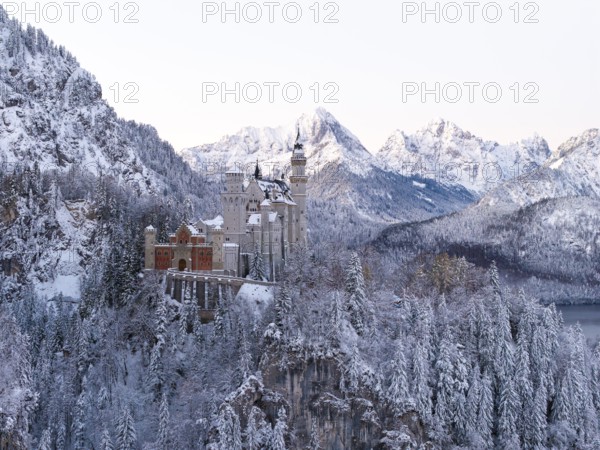Neuschwanstein Castle sits majestically in the midst of a snowy, alpine winter landscape, Schwangau