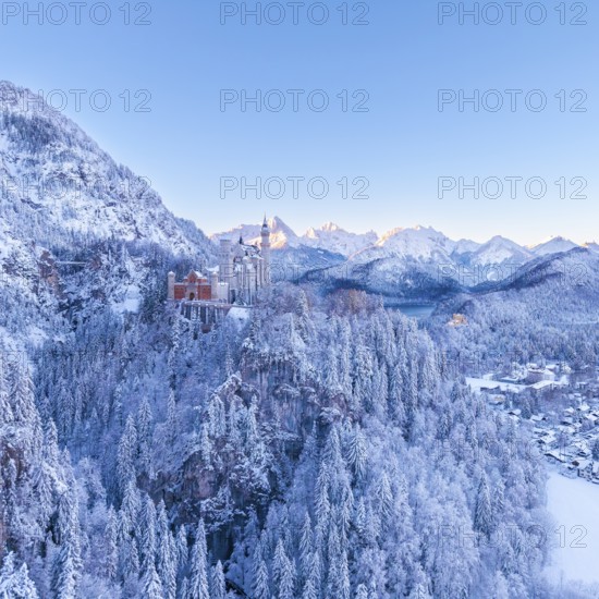 Neuschwanstein Castle rises above a snowy mountain landscape, wrapped in the cold of winter
