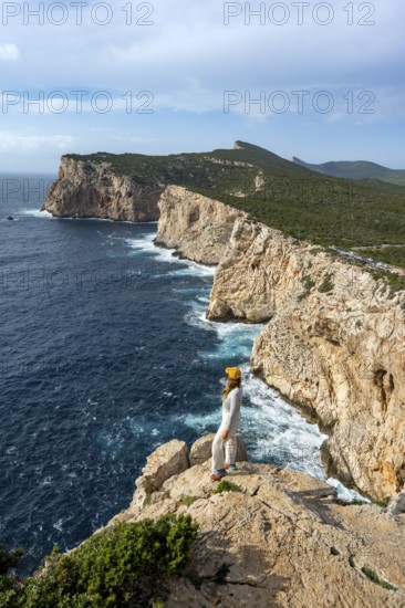 Tourist enjoying the view of steep cliffs by the sea, coastal landscape, cliffs on the Capo Caccia