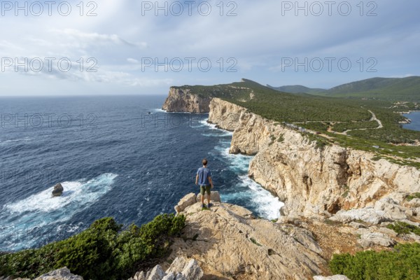 Tourist enjoying the view of steep cliffs by the sea, coastal landscape, cliffs on the Capo Caccia