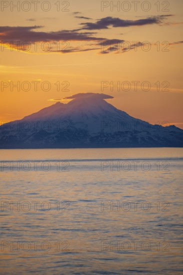 View of Cook Inlet on white mountain peaks of Mount Redoubt at sunset, picturesque golden light of