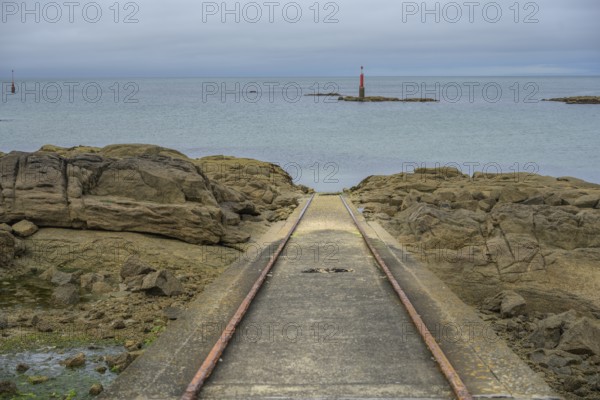 Rusted tracks lead into the sea behind beacons, Barfleur, Manche department, France