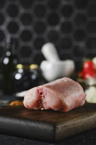 Close-up view of a piece of raw rabbit meat on a wooden cutting board in a contemporary kitchen.