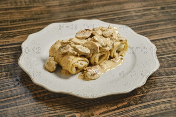 Tasty crepes filled with savory meat and topped with a creamy mushroom sauce, served on a