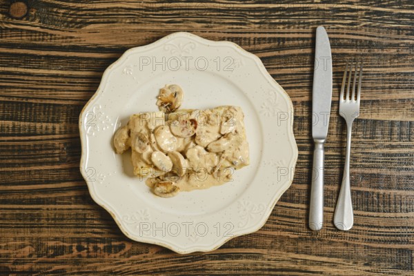 Crepes filled with seasoned meat, topped with a rich and creamy mushroom sauce. The dish is