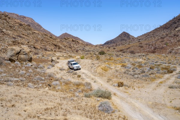 Toyota Hilux off-road vehicle on a sandy track, desert landscape with Brandberg, Erongo,
