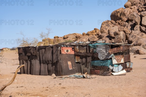 Simple poor huts made of corrugated iron and wood, desert landscape, barren landscape with hills of