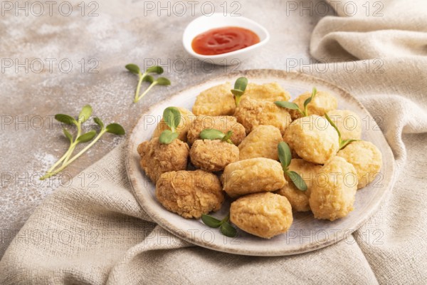 Fried crispy Chicken Nuggets with ketchup, microgreen on brown concrete background and linen
