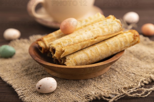 Waffles with caramel on brown wooden background and linen textile, cup of coffee, side view,
