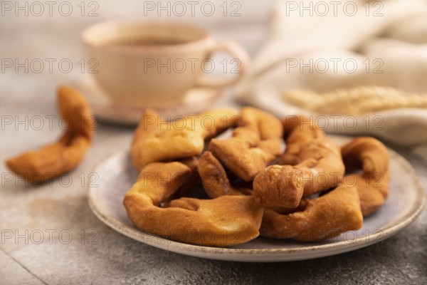 Crunchy biscuit Brushwood cookies sprinkled with powdered sugar on brown concrete background and