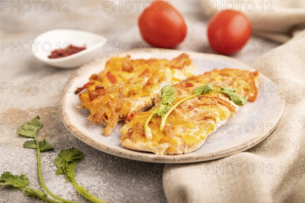Baked chicken meat with cheese and tomatoes on brown concrete background and linen textile. side