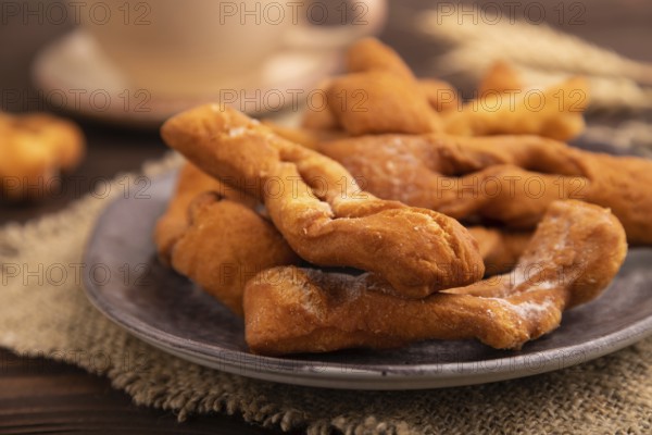 Crunchy biscuit Brushwood cookies sprinkled with powdered sugar on brown wooden background and