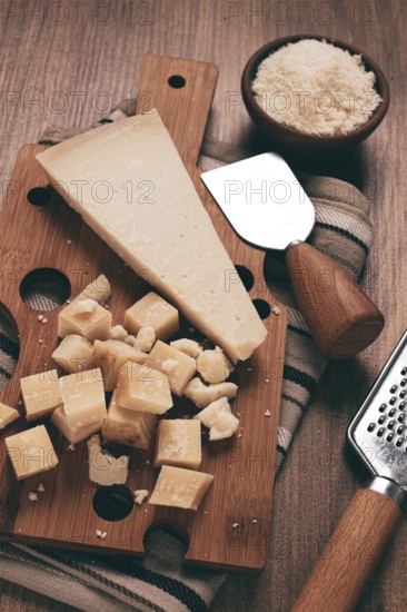Freshly sliced and grated cheese, parmesan cheese, Gran gusto. Grana padano. on a wooden chopping