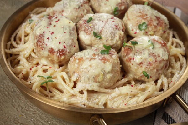 Spaghetti with chicken meatballs, with cream sauce, and parmesan cheese, and decorated with