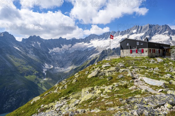 Mountain hut Bergseehütte with Swiss flag in picturesque mountain landscape, view of Damma Glacier