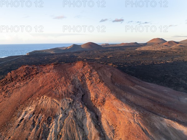 Picturesque volcanic landscape in evening light, red volcano Montaña Bermeja between lava fields,