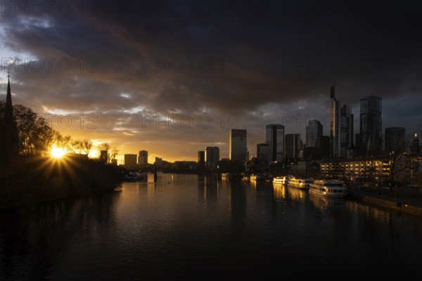 The sun sets behind the Main and bathes Frankfurt's banking skyline in orange-yellow light, Alte