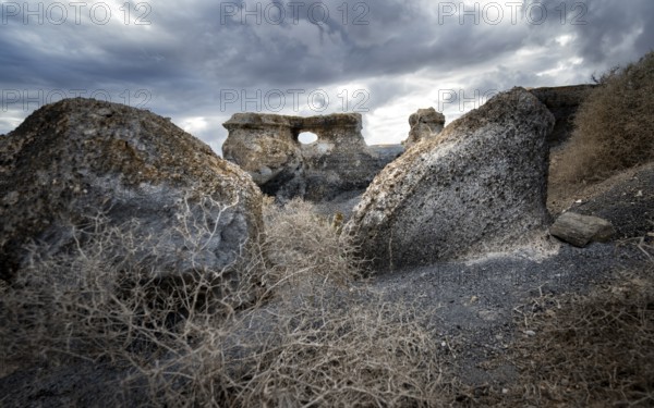 Eroded rock formations with rock tunnels, volcanic landscape with dramatic cloudy skies, Ciudad