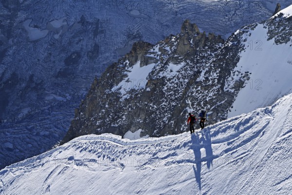 Two ascended mountaineers run across a snow-covered mountain ridge, Aiguille du Midi,
