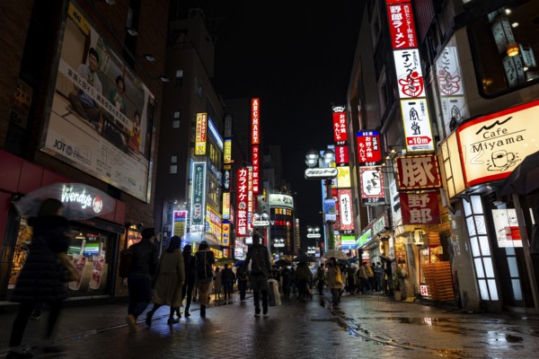 Busy pedestrian zone with many shopping centers and stores, illuminated with lots of neon signs at
