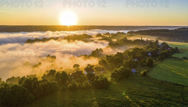 Sunrise over a fog covered village in a rural landscape, golden morning light, serene autumn