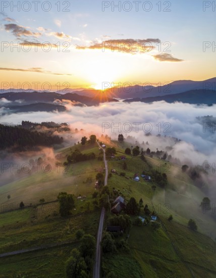 Sunrise over a fog covered village in a rural landscape, golden morning light, serene autumn