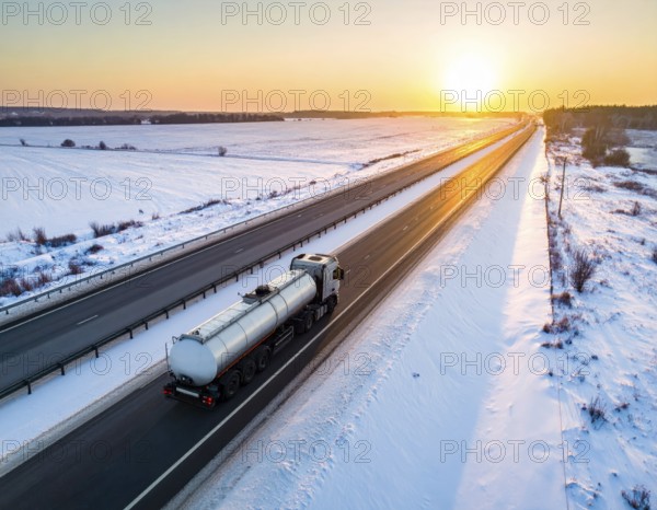 Petrol cargo truck lorry tanker driving on highway hauling oil products at sunrise, wide snowy
