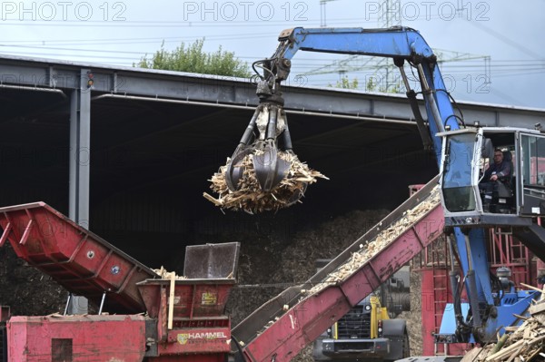 Loading crane with grab arm for loading wood waste for wood pellet production on the premises of