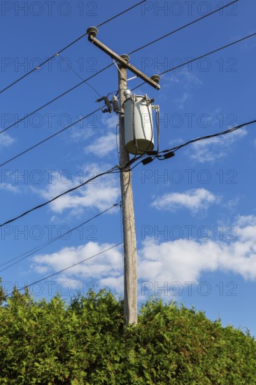 Electricity transformer, high voltage transmission wires, internet, telephone cables attached to