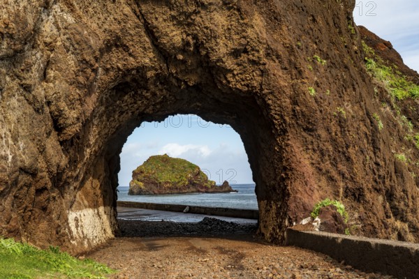 View of the small island of Ilhéu da Ribeira da Janela, Madeira, Portugal, through a tunnel carved