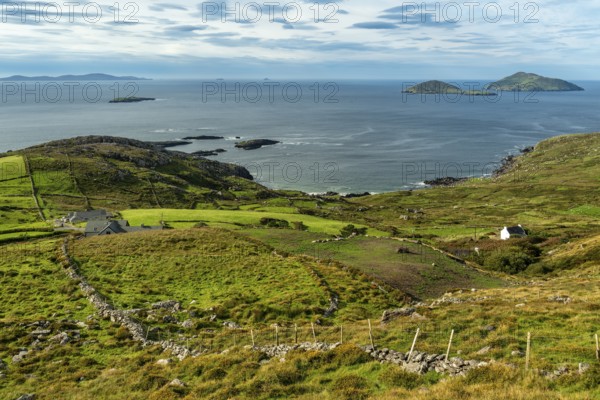 Elevated view over green meadows bordered by natural stone walls and typical cottages to the