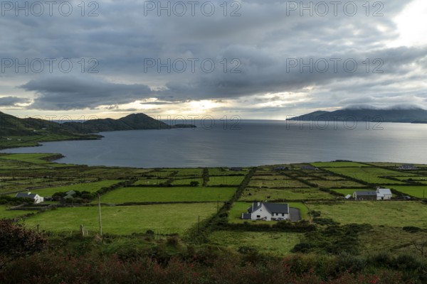 Elevated view over green meadows bordered by natural stone walls and typical cottages to the